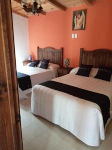 2 camas en una habitación con paredes de color naranja en Casa Manning y Salón la Troje By Rotamundos, en Omitlán de Juárez