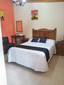 1 dormitorio con 1 cama blanca grande con almohadas negras en Casa Manning y Salón la Troje By Rotamundos, en Omitlán de Juárez