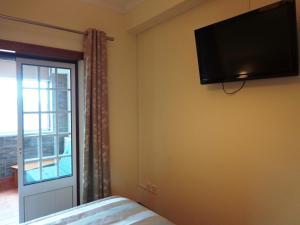 a bedroom with a flat screen tv on the wall at O Vicente in Loriga