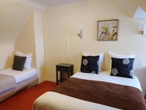 a hotel room with two beds and a picture on the wall at Hotel Du Tertre in Mont-Dol