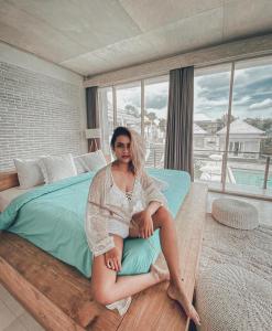 Volcano Terrace Bali في Kintamani: امرأة تجلس على سرير في غرفة النوم