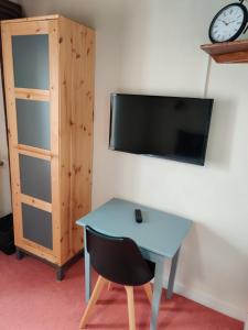 a desk with a chair and a tv on a wall at Hotel Du Tertre in Mont-Dol