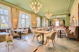 un restaurante con mesas, sillas y lámparas de araña en Villa Antica, en Kudowa-Zdrój