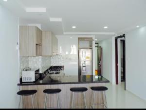 a kitchen with a counter with bar stools and a refrigerator at Cristoforo Oasis in Cartagena de Indias