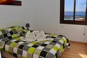 ein Schlafzimmer mit einem schwarzen und grünen Bett mit Handtüchern darauf in der Unterkunft Paradise Ocean View in Los Cristianos