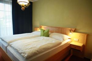 Bett mit weißer Bettwäsche und grünen Kissen in einem Zimmer in der Unterkunft Haus Maria Holzöster in Franking