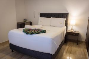 um quarto com uma cama grande com lençóis brancos e almofadas em Samalá Casa Hotel em Pitalito