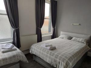 a small bedroom with two beds and a window at The Lodge Guest Accommodation in Barrow in Furness