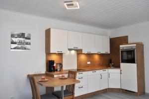 eine Küche mit weißen Schränken und einem Holztisch in der Unterkunft Alte Pastorei Minsen in Wangerland