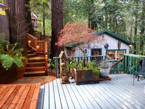 a wooden deck with a house in the woods at Guerneville Cottage! Redwoods! Hot Tub! Fire Table! Fast WiFi!! Serenity Defined! in Guerneville