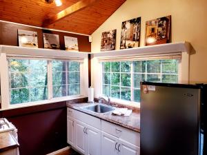 a kitchen with a sink and two windows at Guerneville Cottage! Redwoods! Hot Tub! Fire Table! Fast WiFi!! Serenity Defined! in Guerneville