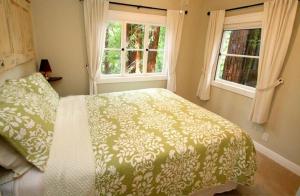 una camera da letto con un letto e due finestre di Little Red House! Redwoods! Hot Tub! BBQ! Fast WiFi!! Multiple Decks!! Near Golf Course!! Dog Friendly! a Guerneville