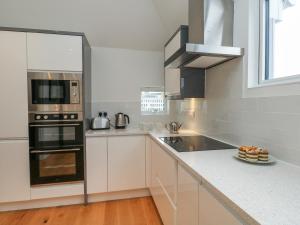 a kitchen with white cabinets and black appliances at Harbourside Haven Penthouse 1 in Weymouth