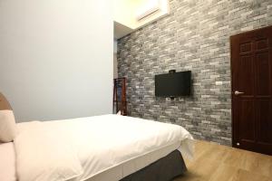 a bedroom with a bed and a tv on a brick wall at 蘑燈民宿 Mushroom Light Homestay in Taitung City