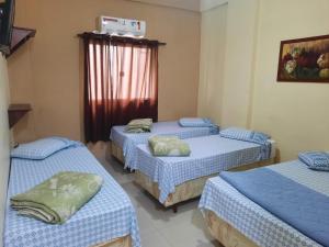 a room with three beds and a window at Pousada Mãe Ternura Palace in Aparecida +37 photos