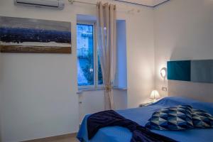 a bedroom with a blue bed and a window at Atrani Rooms in Atrani