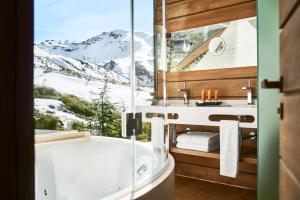 a bathroom with a tub and a window with snow covered mountains at El Lodge, Ski & Spa in Sierra Nevada