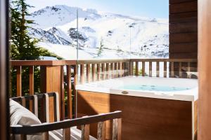 a hot tub on a deck with snow covered mountains at El Lodge, Ski & Spa in Sierra Nevada