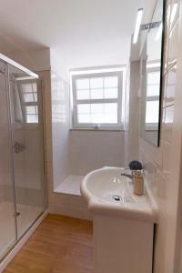 a white bathroom with a shower and a sink at Refúgio de Calheiros in Covilhã