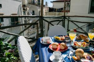 a table with plates of food and drinks on a balcony at Atrani Rooms in Atrani
