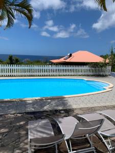 a swimming pool with chairs and a fence at Gîtes BB in Bouillante +33 photos