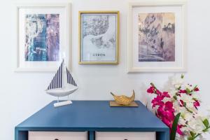 リスボンにあるGuesthouse Liberdade - 7 Bedroom Apartmentの青い机、絵画が描かれた壁に模型ボートが備わります。