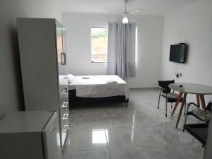 um quarto com uma cama, uma mesa e uma janela em Flat 302 em Ubá