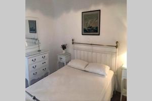 a white bedroom with a bed and a dresser at Pigeon House Ornos Beach in Mikonos