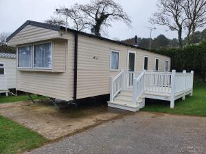 uma casa móvel com um alpendre branco e escadas em Cozy 3 bedroom Caravan, Sleeps 8, at Parkdean Newquay Holiday Park em Newquay
