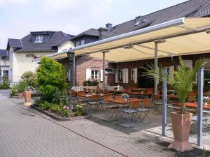 eine Terrasse mit Tischen und Stühlen unter einem Pavillon in der Unterkunft Hotel Auerhahn in Pulheim