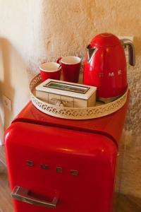 einem roten Kühlschrank mit Tassen und einem Wasserkocher darüber in der Unterkunft La Corte Dei Pastori Luxury in Matera