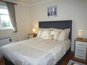 - une chambre dotée d'un grand lit avec des draps et des oreillers blancs dans l'établissement Mountain View Holiday Home, à Louisburgh