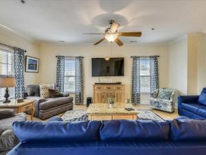 Ocean View Luxury Rental - Sleeps 16 في ميرتل بيتش: غرفة معيشة مع أريكة زرقاء ومروحة سقف