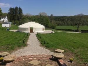 Penbedw Estate -Rural retreats,tennis في مولد: خيمة بيضاء في حقل عشبي مع مسار