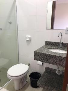 a bathroom with a toilet and a sink and a mirror at Hotel Bee's Sorriso in Sorriso