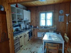 cocina con paredes de madera, mesa y ventana en Faház Hejce en Hejce