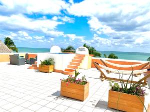 eine Terrasse mit einem Stuhl, Blumen und dem Meer in der Unterkunft Seaside Villas in Caye Caulker