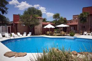 a large swimming pool with chairs and umbrellas at Cabañas La Aldea in Villa Carlos Paz