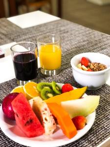 un plato de fruta en una mesa con un vaso de zumo en Hotel Di Sica, en Balneário Camboriú 23 fotos más