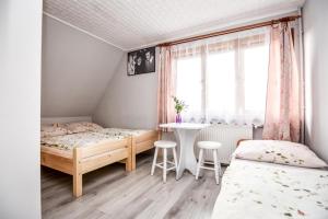 a bedroom with two beds and a table and a window at Dom Wypoczynkowy u Ewy in Biały Dunajec