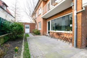 eine Terrasse außerhalb eines Backsteingebäudes mit Stühlen in der Unterkunft RAJ Living - 1 , 3 and 4 Room Apartments - 20 min MESSE DUS & Airport DUS in Meerbusch