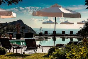 a swimming pool with chairs and umbrellas at Tenuta Del Poggio Antico in Ischia