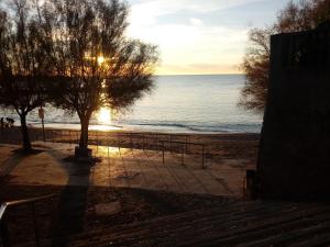 a view of a beach with the sun setting over the water at Caletta Beach in Castiglioncello