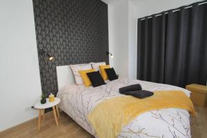 1 dormitorio con 1 cama con almohadas amarillas y negras en Le Refuge by EasyEscale, en Romilly-sur-Seine