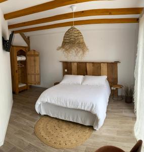 ein Schlafzimmer mit einem weißen Bett und einem Kronleuchter in der Unterkunft Le Clos Bleu - Gite Rural in Schillersdorf