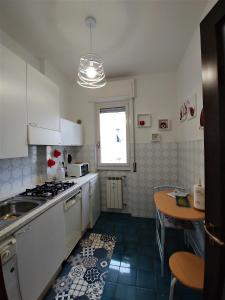 ラパッロにあるSun Flatの白いキャビネット、シンク、テーブル付きのキッチンが備わります。