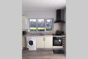 a kitchen with white cabinets and a washer and dryer at Mews with garden views in Carlow