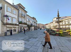 a man walking down a street in a town at A Botoeira da Praça guest house in Viana do Castelo
