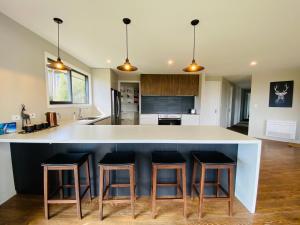 a kitchen with a white counter and bar stools at Lake Views at Antler Lodge in Lake Tekapo