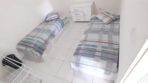 a bedroom with two beds and a white tiled floor at Ap06-A 50 Metros da Praia Flats Mobiliados para 4 Pessoas in Paulista